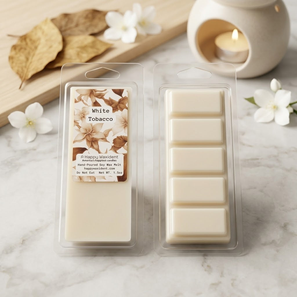 Packaged wax melts with a 'White Tobacco' label on a marble surface with flowers and a candle.
